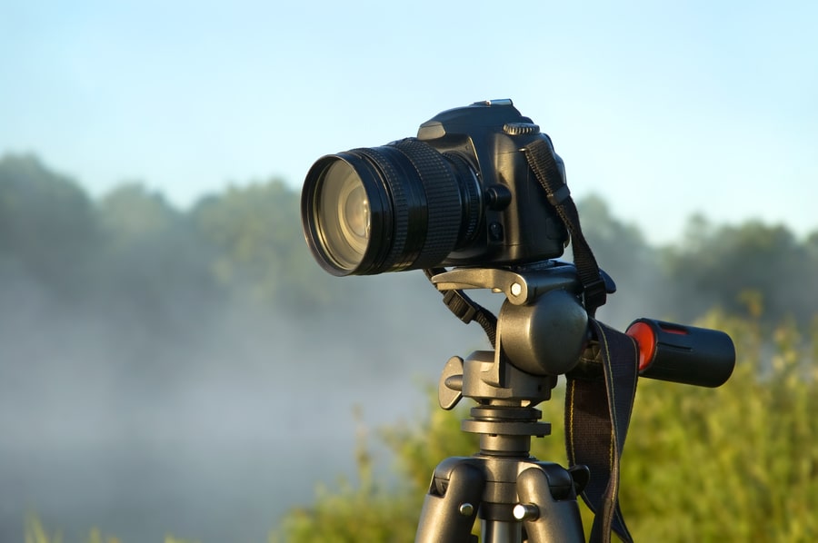 Camera on tripod against a river background.