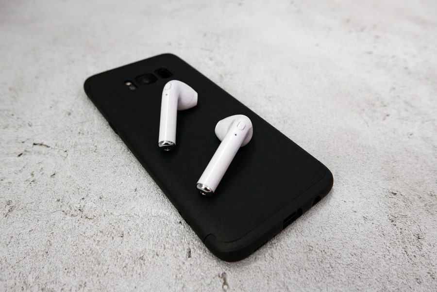 White wireless earphones on a black mobile phone. 