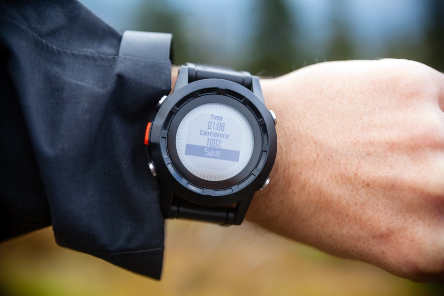 Hiker on mountain trail looking at sportswatch checking direction on electronic compass.