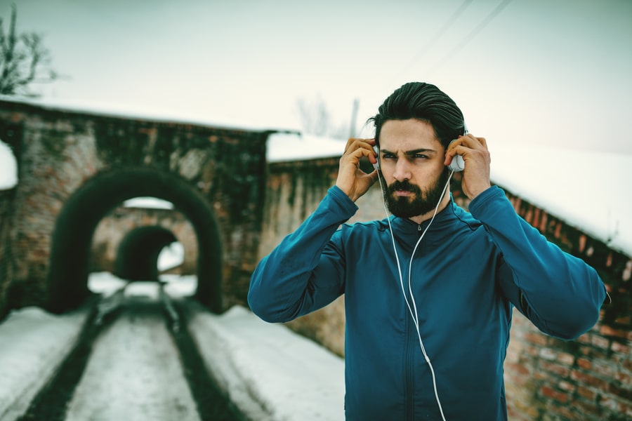 A male runner with headphones on his ears listen electronic music and prepare to run